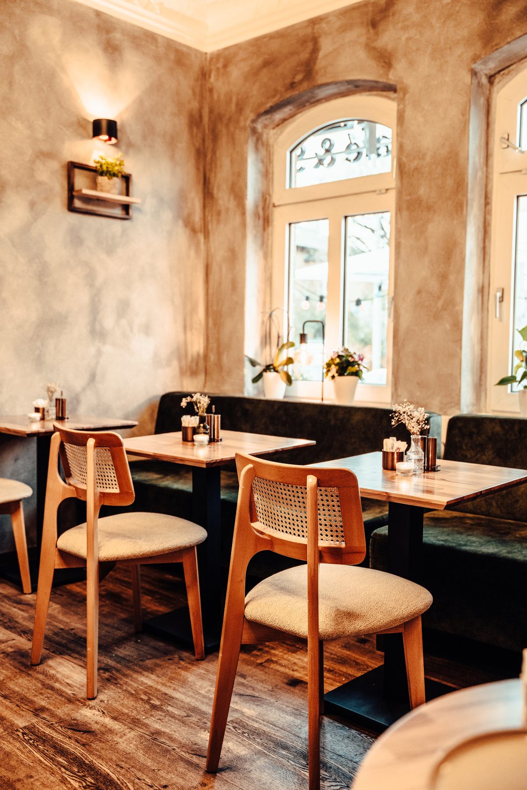 Das Brekkie Interior — warmes Licht, Bogenfenster, Rattanstühle